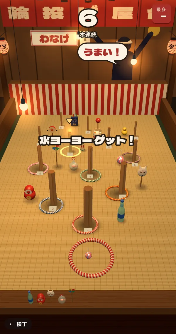 輪投げのプレイ画面。夜の縁日の屋台で、番号つきの棒に色とりどりの輪が掛かり、景品が並んでいる